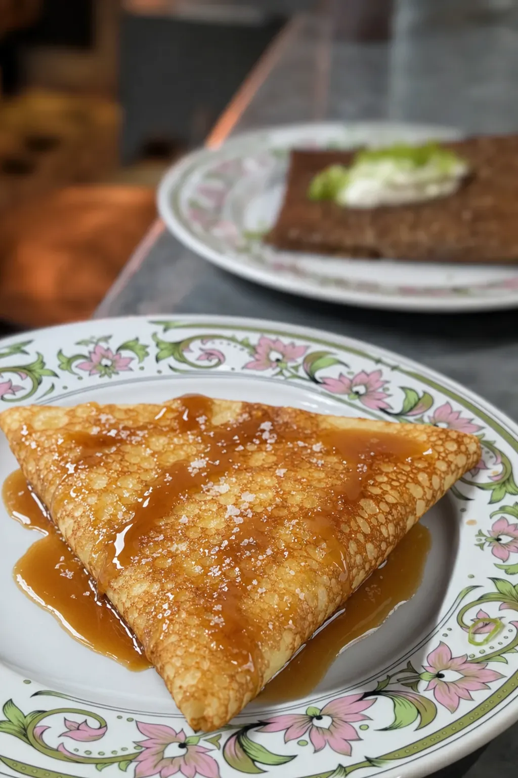 Crêpe de froment au caramel au beurre salé, pliée en quatre sur assiette fleurie