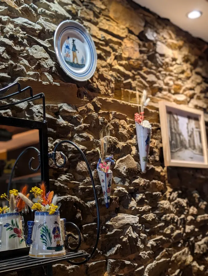 Salle de la crêperie Mamilig à Châteaugiron : murs de pierre et faïences bretonnes